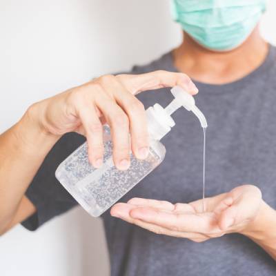 Smiling staff/guests with sanitiser stations visible in the background